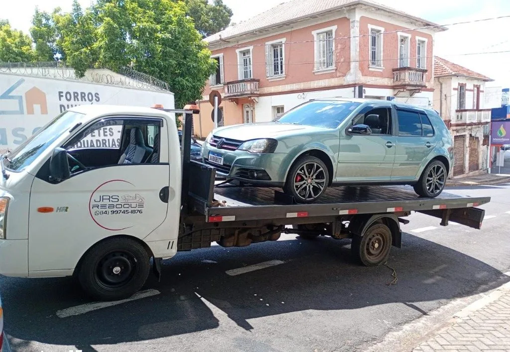 Caminhão guincho plataforma transportando carro de passeio Golf com segurança em Botucatu